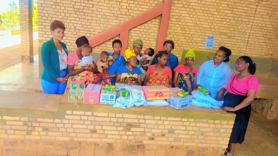 Director and mothers with children receiving nutritional support packages